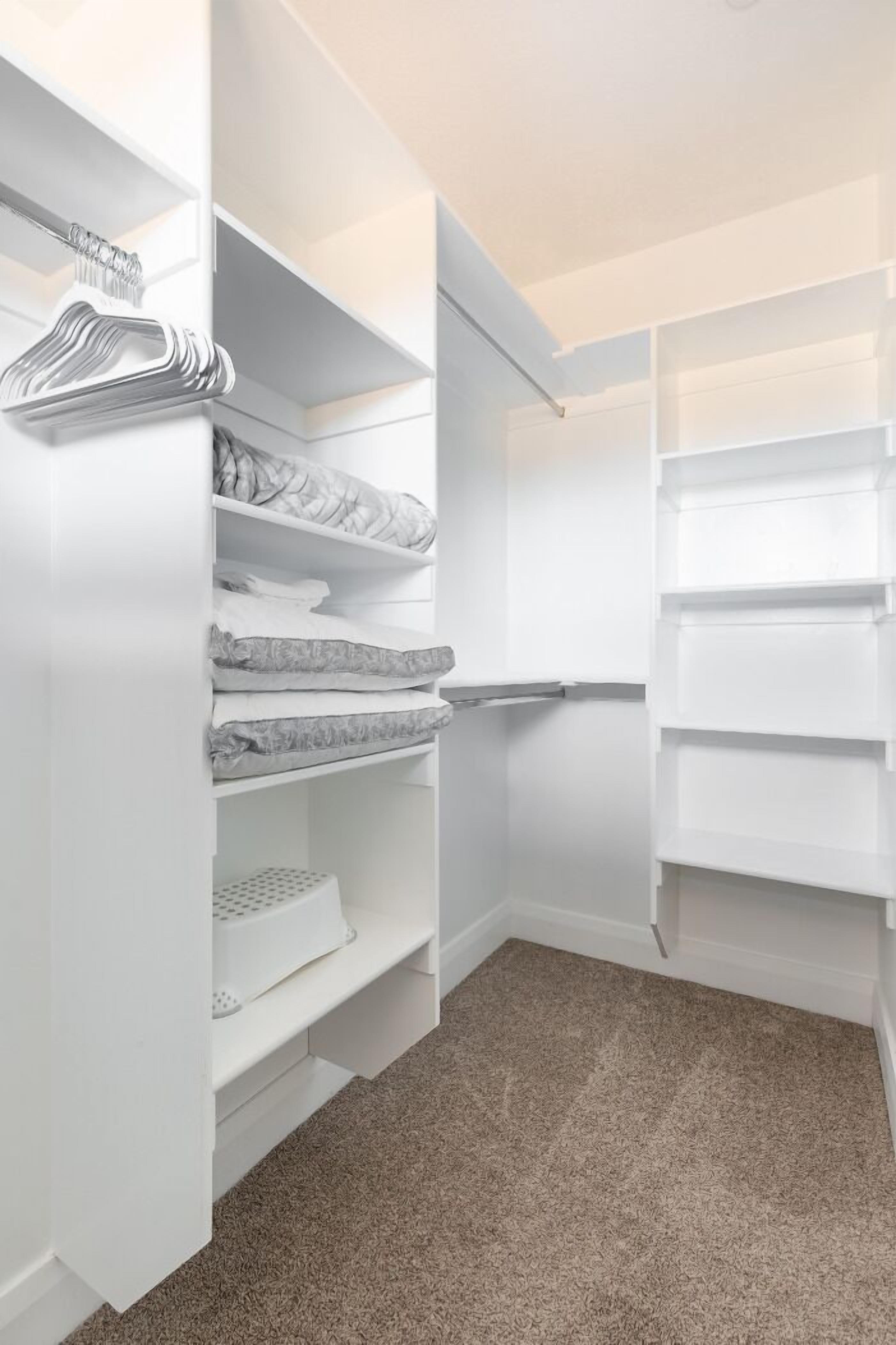 A walk-in closet with open shelving, a hanging rod, and a shoe rack.