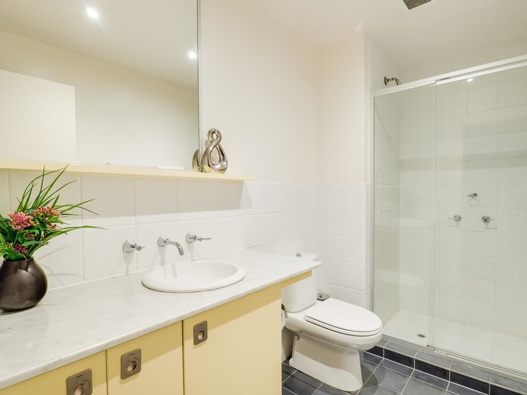 A bathroom with a white sink, toilet, and glass shower enclosure.