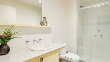 A bathroom with a white sink, toilet, and glass shower enclosure.