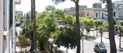 A street view with trees, a building, and a parked car.