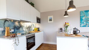 A modern kitchen with white cabinets, a built-in oven, and a central island with a sink. - Luxury what ever the weather (Wellington)