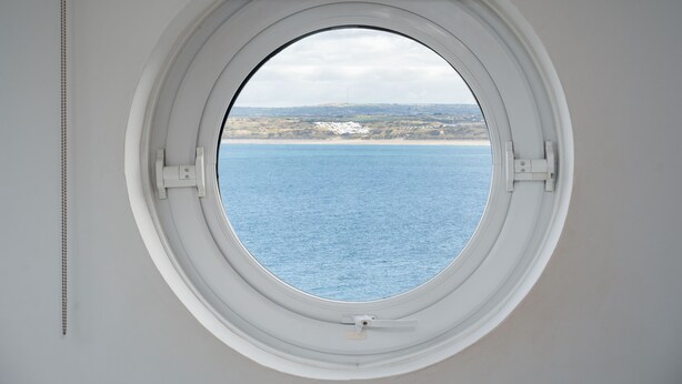 Een rond raam met uitzicht op zee en een verre horizon.