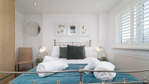 Een keurig opgeruimde slaapkamer met een bed, een stoel en een raam met jaloezieën.