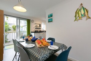A dining area with a table set for two, featuring croissants and watermelon slices.