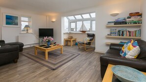 Een moderne woonkamer met een bank, salontafel en boekenkasten.
