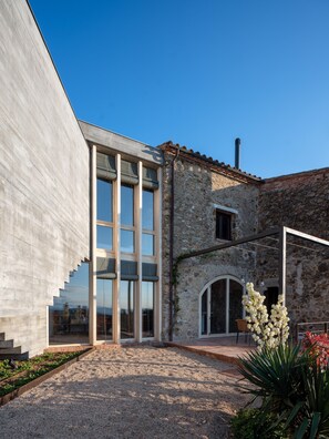 A modern building with a concrete facade, large windows, and a stone structure with a tiled roof. - Holiday rental townhouse with swimming pool in Begur, Centre (Begur)