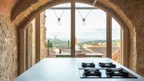 A kitchen with a large window, stone walls, and a view of the countryside. - Holiday rental townhouse with swimming pool in Begur, Centre (Begur)