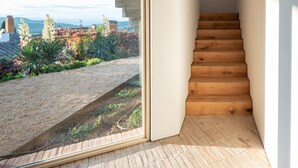 A modern interior with a concrete ceiling, a wooden staircase, and a large window offering a view of a garden and distant landscape. - Holiday rental townhouse with swimming pool in Begur, Centre (Begur)