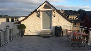 A rooftop terrace with a small building, a potted plant, and outdoor furniture. - Friendly Home - "Helles Dachstudio" - Cologne - Fair - Bonn - Phantasialand (Bornheim)