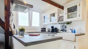 A kitchen with white cabinets, a granite countertop, a microwave, a coffee maker, and a window providing natural light. - Friendly Home - "Helles Dachstudio" - Cologne - Fair - Bonn - Phantasialand (Bornheim)