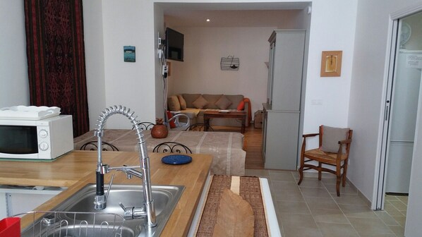 A compact kitchen with a sink, a microwave, and a dining area with a table and chairs. - 3 star furnished comfortable, newly renovated, quiet historic center (Castellane)