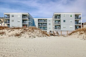A beachfront apartment complex with multiple balconies and a sandy beach in the foreground. - BEACHFRONT top-floor Condo next to Garden City pier with PRIVATE POOL! (Murrells Inlet)