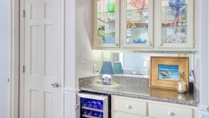 Una cocina con armarios blancos, encimera de granito y vitrina de vidrio integrada para objetos decorativos.