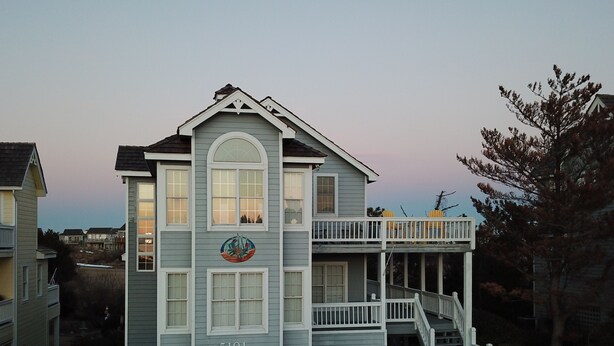 A two-story house with a balcony and a garage. - Two Crabby: Feels like home! Spectacular views, Beach Club Summer 2026! (Nags Head)