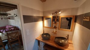Une salle de bain avec un meuble-lavabo en bois, deux vasques, un miroir et un porte-serviettes.