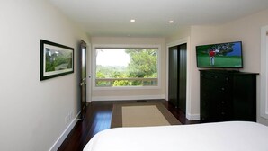 A bedroom with a large window, a bed, a television, and a dresser. - Jack's Peak Retreat (Carmel)