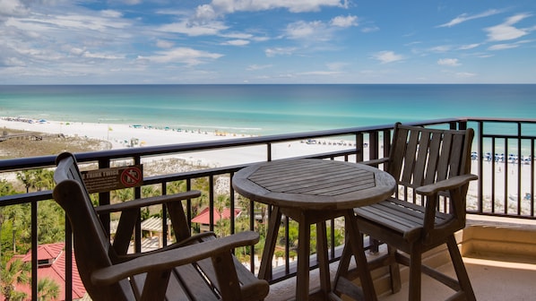 A balcony with a table and chairs overlooking a beach. - Golf Cart ~ Beach Front ~ Balcony ~ Community Pool (Miramar Beach)