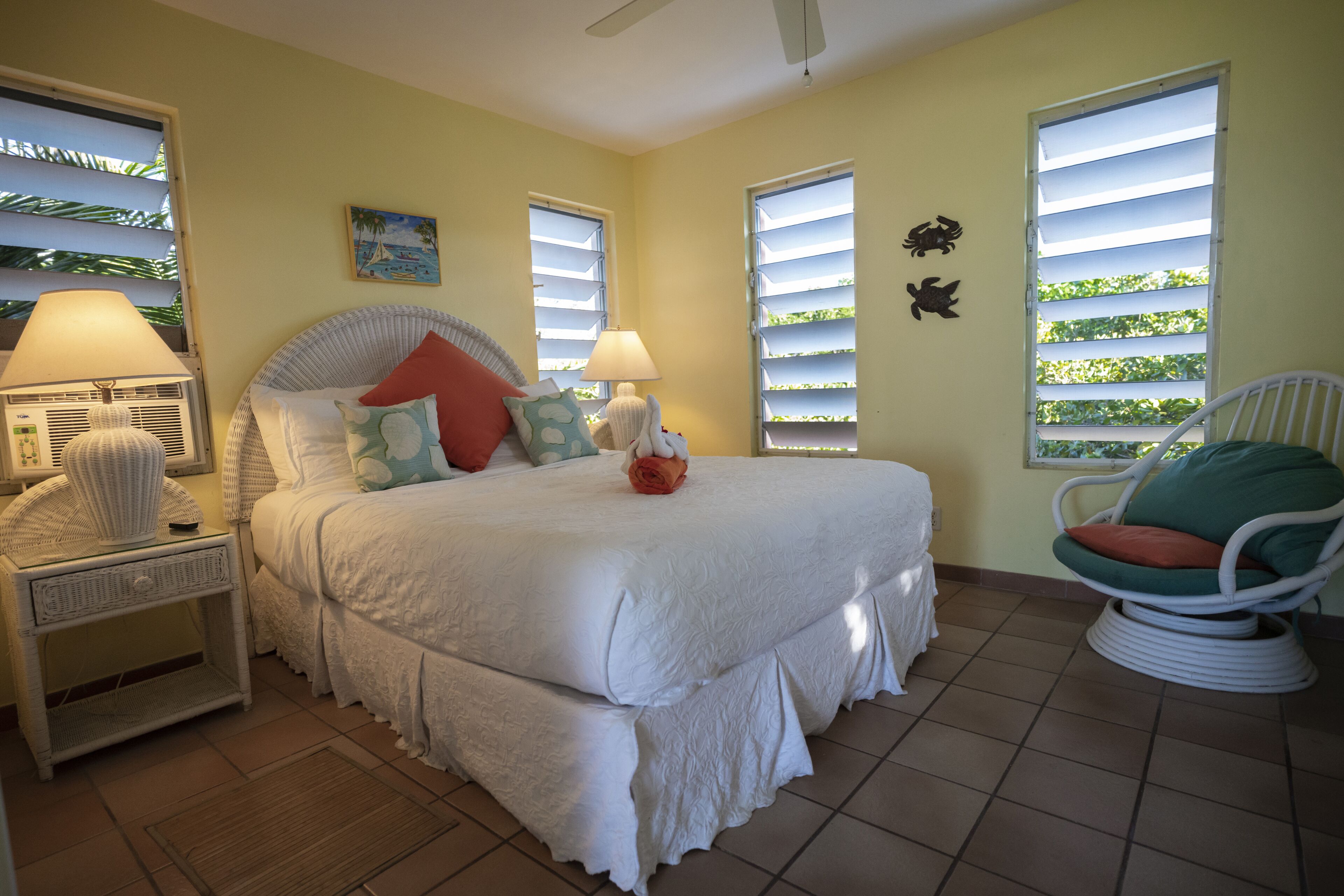 A bedroom with a bed, two nightstands, a chair, and a window with shutters.