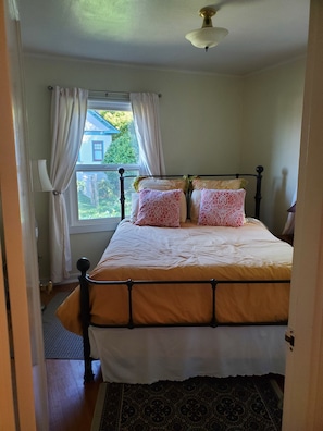 Un dormitorio con cama, cortinas, ventana y ventilador de techo.