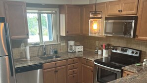 A kitchen with granite countertops, stainless steel appliances, wooden cabinets, and a window providing natural light. -  Family/ Pet Friendly Downtown Winter Park Condo 3BD/2BA (Winter Park)