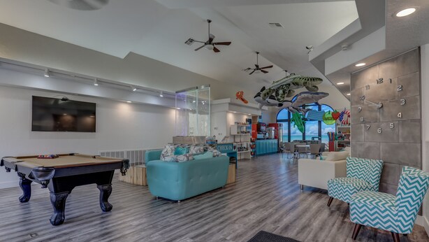 A spacious living area with a pool table, teal and white sofas, and a modern ceiling fan. - Pure Comfort - 3 bedroom/2 bath Las Palmas Condo  (St George)