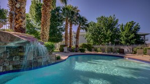 A swimming pool with a stone waterfall, surrounded by palm trees and lounge chairs. - Pure Comfort - 3 bedroom/2 bath Las Palmas Condo  (St George)