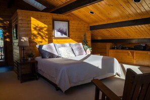 Une chambre confortable dans un chalet, avec un plafond en bois, un lit recouvert de draps blancs, une petite table et une chaise.