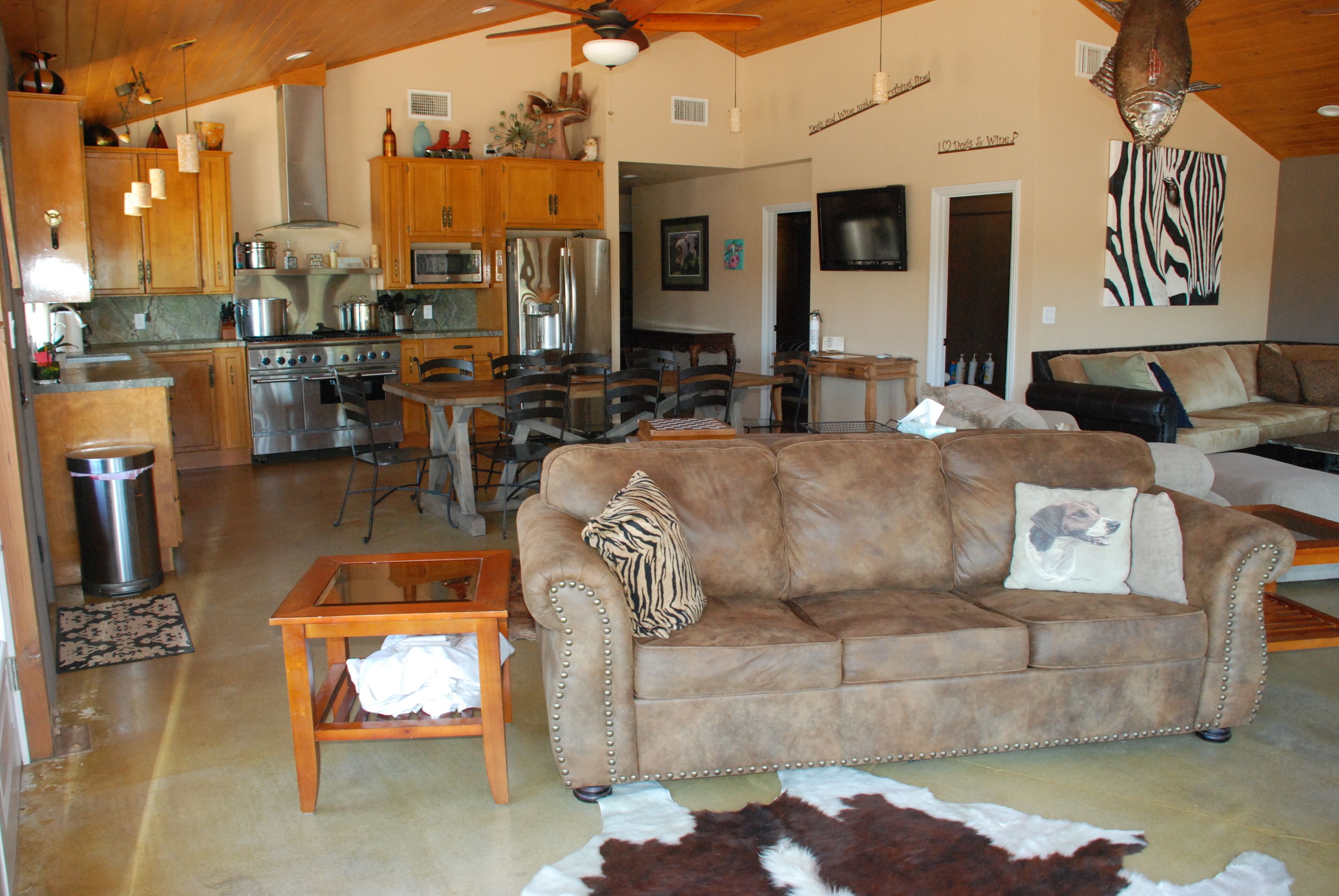 A spacious living area with a leather sofa, a dining table, and a kitchen in the background.