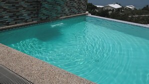 A swimming pool with clear water, surrounded by a pebble border and a tiled wall. - Seaview Mansion (Dalaguete)