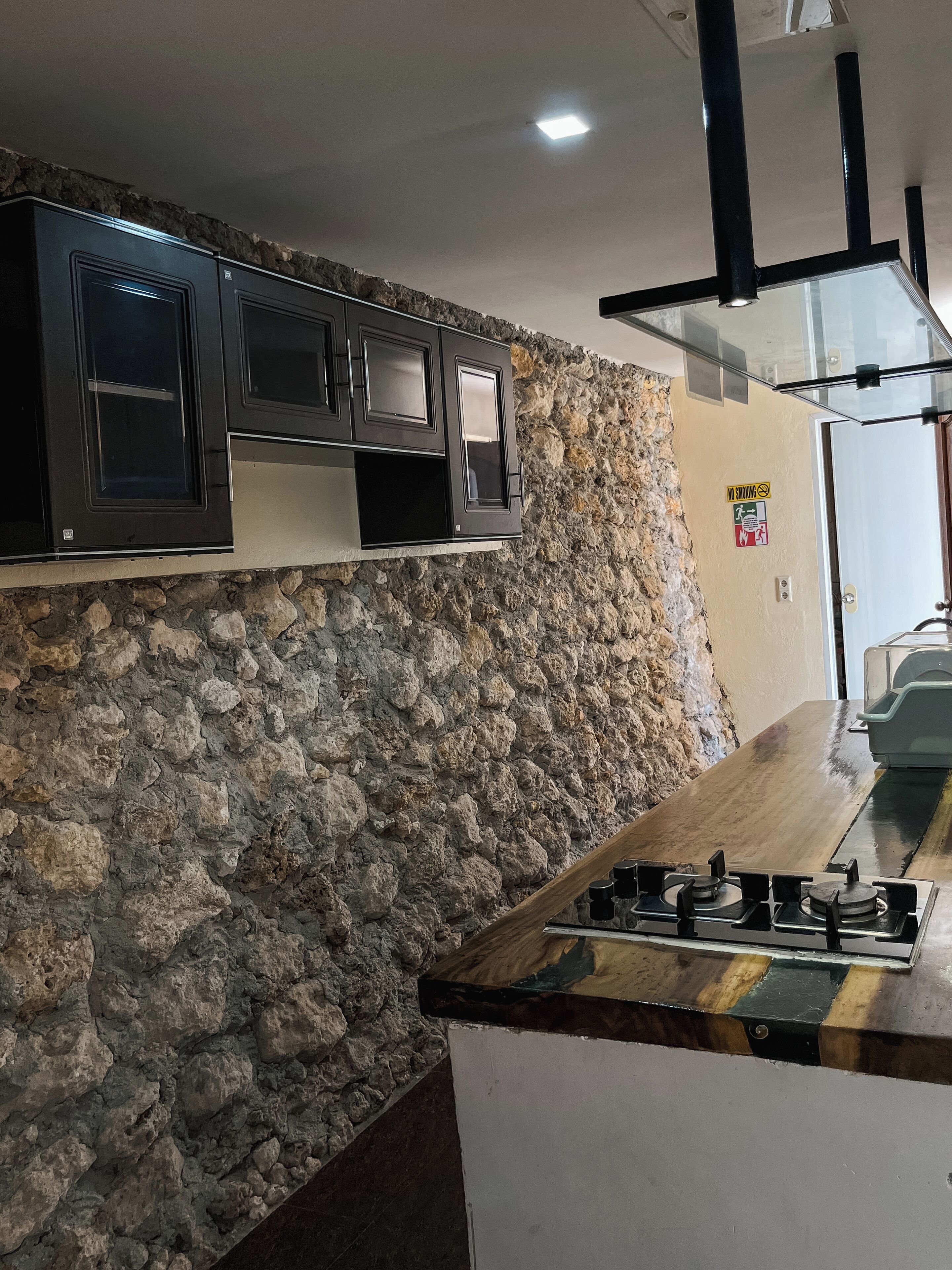 Eine Küche mit Steinwand, schwarzen Schränken und einem Gasherd.