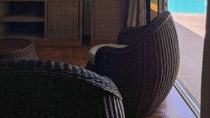 A modern living room with a flat-screen TV, wicker furniture, and a view of a swimming pool. - Seaview Mansion (Dalaguete)