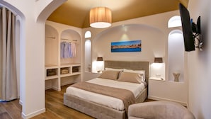 Une chambre avec un grand lit, des étagères intégrées, un tableau et un téléviseur fixé au mur.