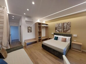 A modern bedroom with a large bed, built-in shelving, and a painting on the wall.