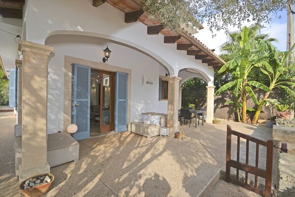 Una villa con un porche cubierto, mobiliario exterior y un sendero de piedra.