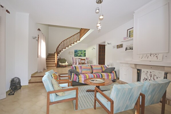 A spacious living room with a staircase, a sofa set, and a fireplace.