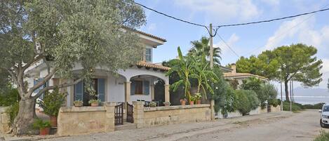 Una propiedad residencial con entrada pavimentada, pared de piedra y plantas en macetas.