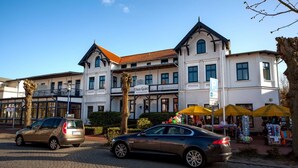 A building with a sign reading "Haus Grahl" and a parking area with two cars.