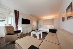 Une chambre d’hôtel moderne équipée d’un canapé, d’un fauteuil et d’un téléviseur à écran plat.