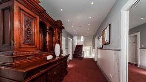 A hallway with a grand wooden console table, a staircase, and a red carpet.