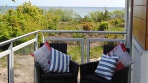 Ein Balkon mit Korbstühlen, einem Tisch mit Früchten und Blick aufs Meer.