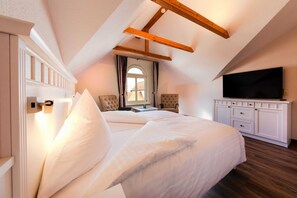 Une chambre avec un grand lit, une télévision et une poutre en bois au plafond.