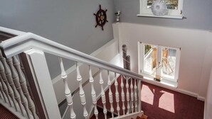 A staircase with white balusters and a red carpeted landing.