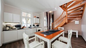 Eine moderne Küche mit weißen Schränken, einem Holztisch und einer Treppe.