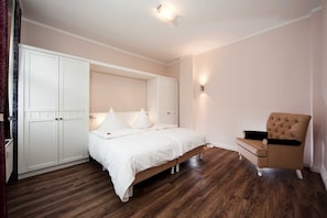 A bedroom with a bed, a chair, and a wardrobe.