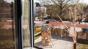 A view from a window overlooking a playground with a wooden structure and sand.