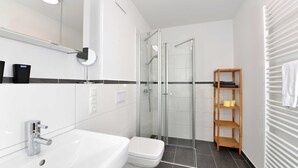 Uma casa de banho moderna com lavatório branco, sanita e cabine de duche em vidro.