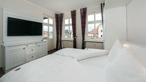 A hotel room with a large bed, a TV mounted on the wall, and a window with curtains. - Apartment Königsstuhl - House Grahl GM 69912 (Graal-Müritz)