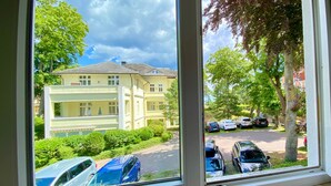 A window view of a building with parked cars and greenery. - House Nemo, App. 8, Germany (Heringsdorf)