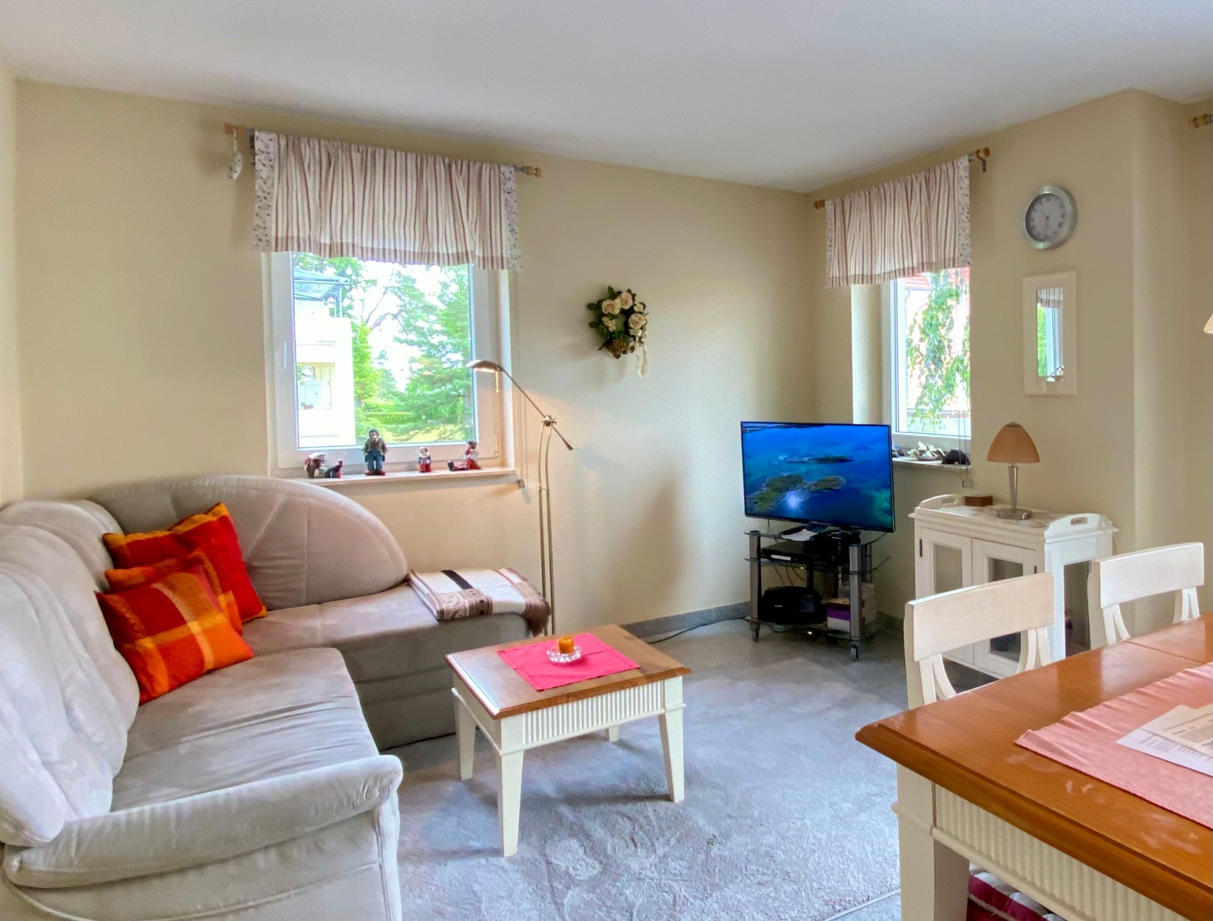 Uma sala de estar com sofá, mesa de centro, televisão e um espaço de jantar com cadeiras.