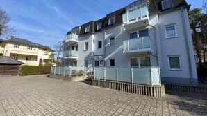 A multi-story residential building with balconies, a paved driveway, and a clear sky. - House Nemo, App. 8, Germany (Heringsdorf)